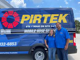 man and a woman standing in front of a pirtek truck
